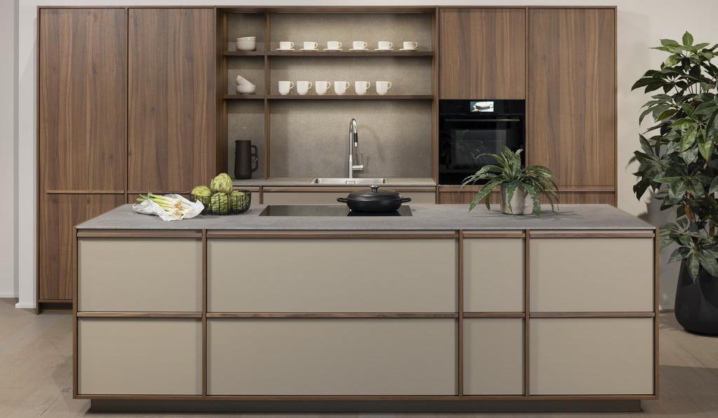 LEICHT Kücheninsel Japandi-Fronten Holzleisten auf matt lackierten Fronten sandfarben dahinter Hochschränke in Echtholz